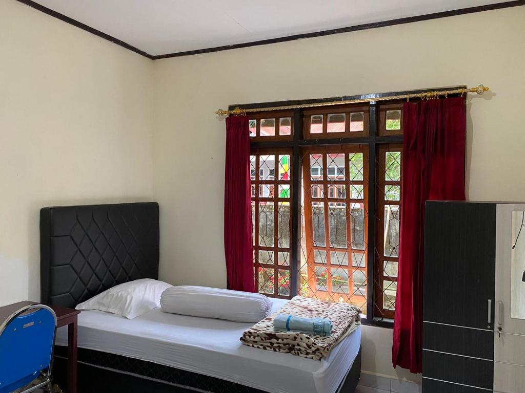 a bedroom with a bed and a window with red curtains at Mawar Bed and Breakfast in Bajawa