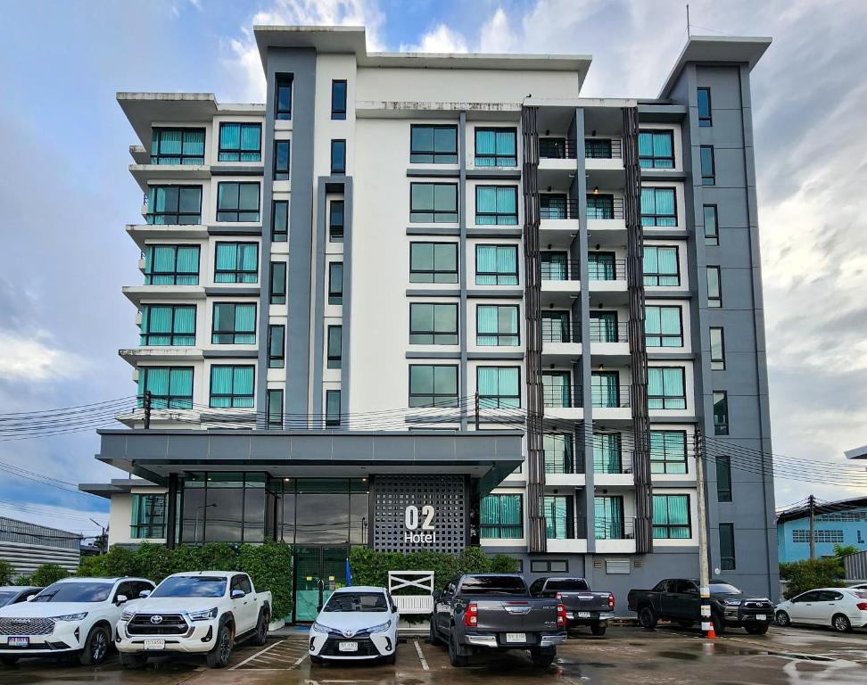 un grand bâtiment avec des voitures garées dans un parking dans l'établissement O2 Hotel Maesot, à Mae Sot