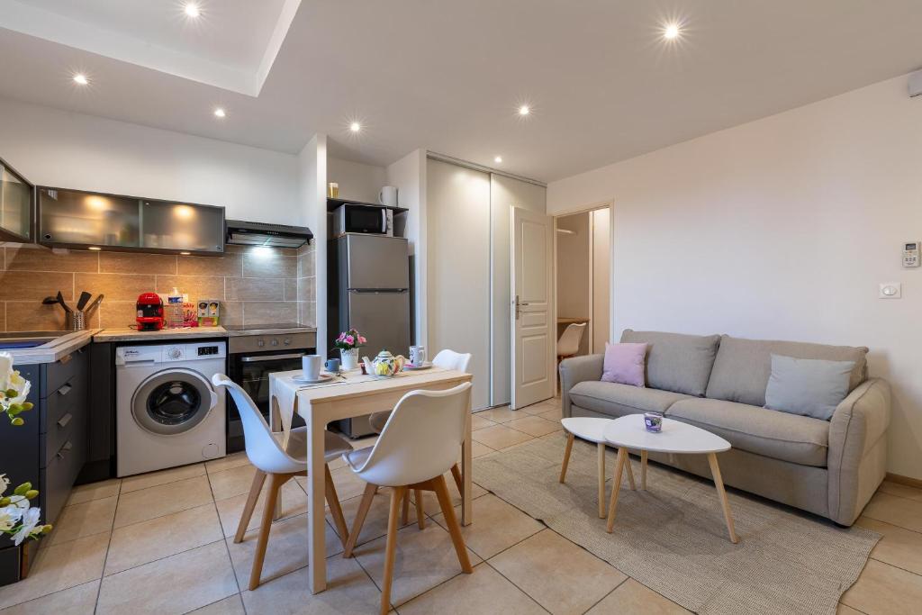 een woonkamer met een bank en een tafel en stoelen bij Coeur de Provence - Appt climatisé in Draguignan