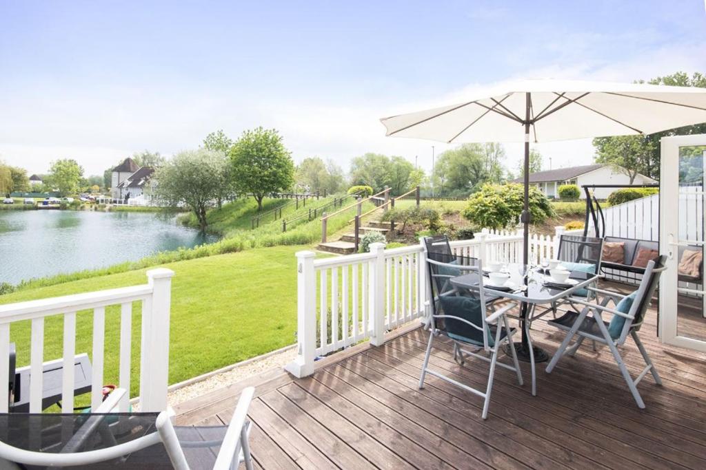 a wooden deck with a table and an umbrella at Isis Lakes 07, Carpe Diem in South Cerney