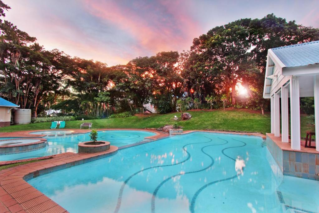 uma piscina com um arco-íris no céu em Caribbean Estates Holiday Resort em Port Edward