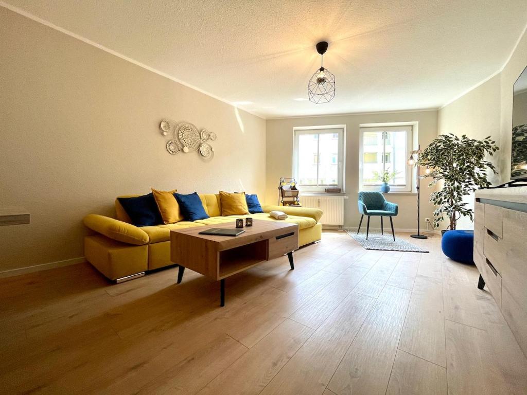 ein Wohnzimmer mit einem gelben Sofa und einem Tisch in der Unterkunft Apartment Uptown im Herzen der Dresdner Neustadt! in Dresden