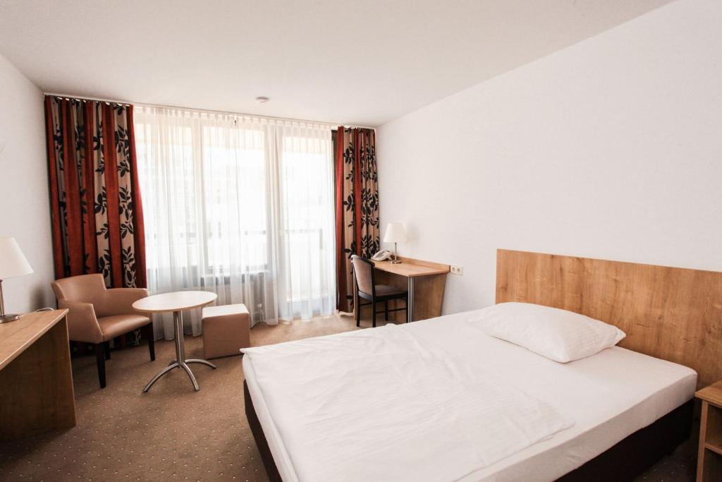 a bedroom with a bed and a desk and a window at Appartis - Boardinghouse am Klostersee in Sindelfingen