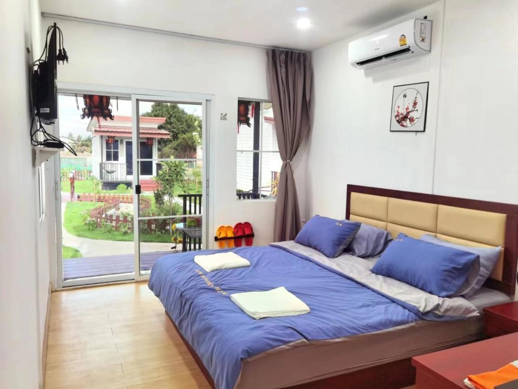 a bedroom with a bed with blue sheets and a window at Love In Kan in Wang Khanai