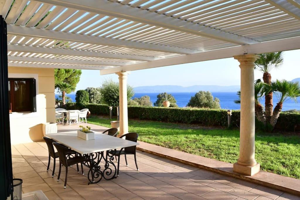 a patio with a table and chairs under a pergola at Villa Althea in Perdika