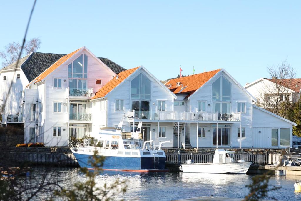eine Gruppe von Häusern mit Booten im Wasser in der Unterkunft Fjordbris Hotel in Østhusvik