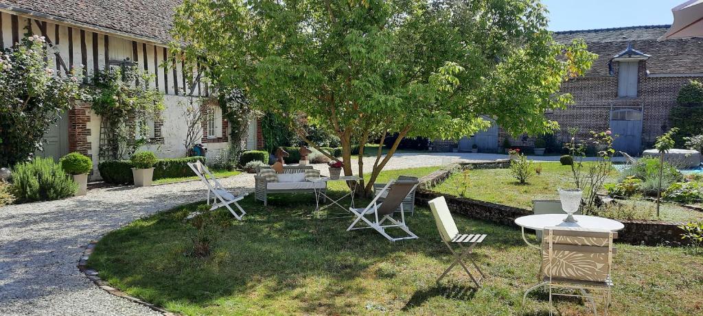 einen Garten mit Stühlen, einem Tisch und einem Baum in der Unterkunft Domaine de la Creuse in Moussey