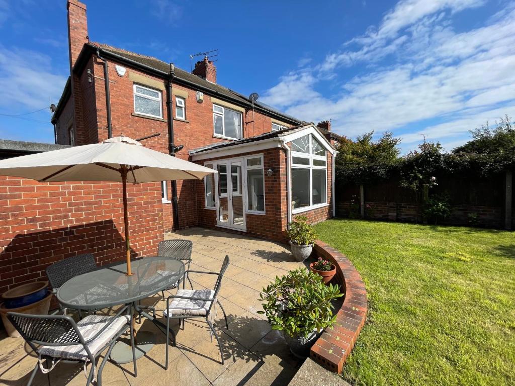 a patio with a table and chairs and an umbrella at Seaview House, Tynemouth - Luxury Family Holiday Home in Tynemouth