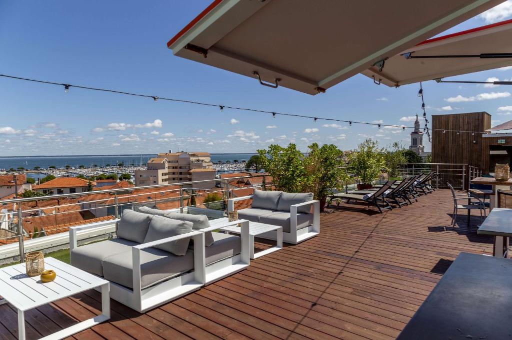 a patio with white chairs and tables on a roof at Best Western Arcachon Le Port in Arcachon