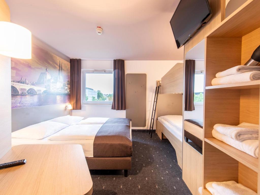 a hotel room with two beds and a desk at B&B Hotel Regensburg-City in Regensburg