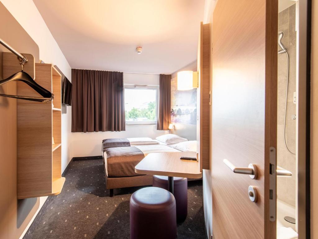 a hotel room with two beds and a table at B&B Hotel Regensburg-City in Regensburg