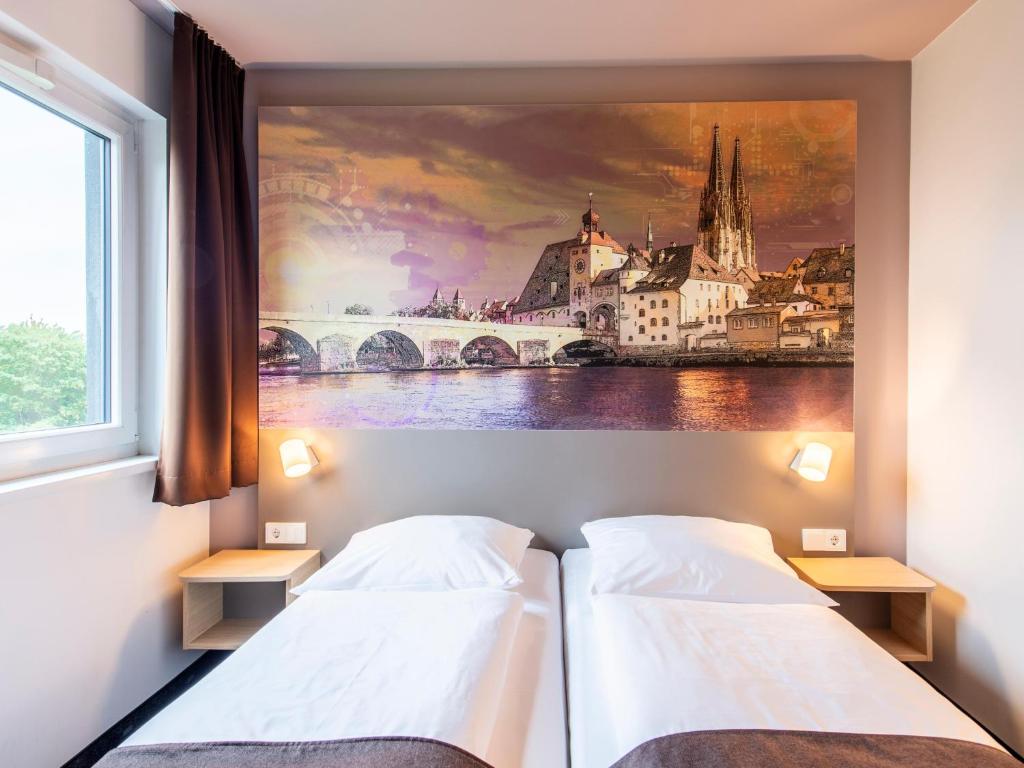 two beds in a room with a painting on the wall at B&B Hotel Regensburg-City in Regensburg