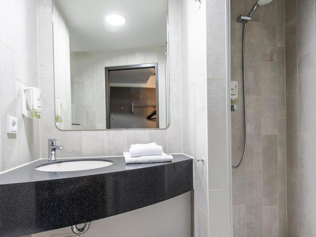 a bathroom with a sink and a mirror at B&B Hotel Regensburg-City in Regensburg