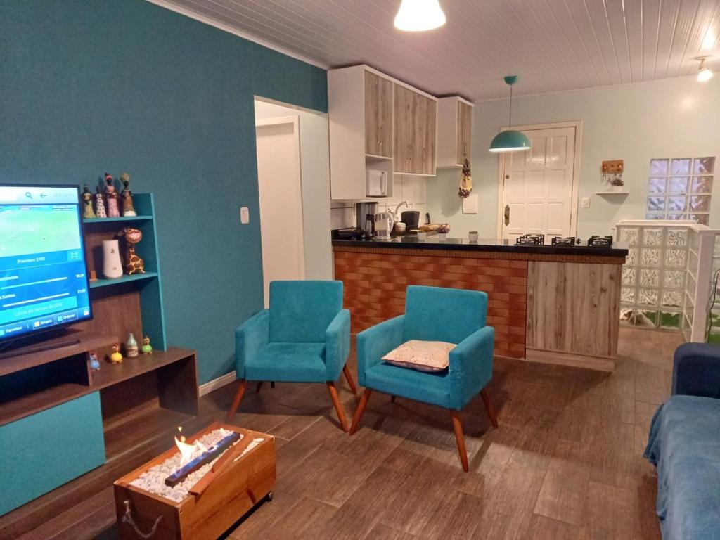 a living room with blue chairs and a kitchen at Casa na Serra Gaucha Canela in Canela