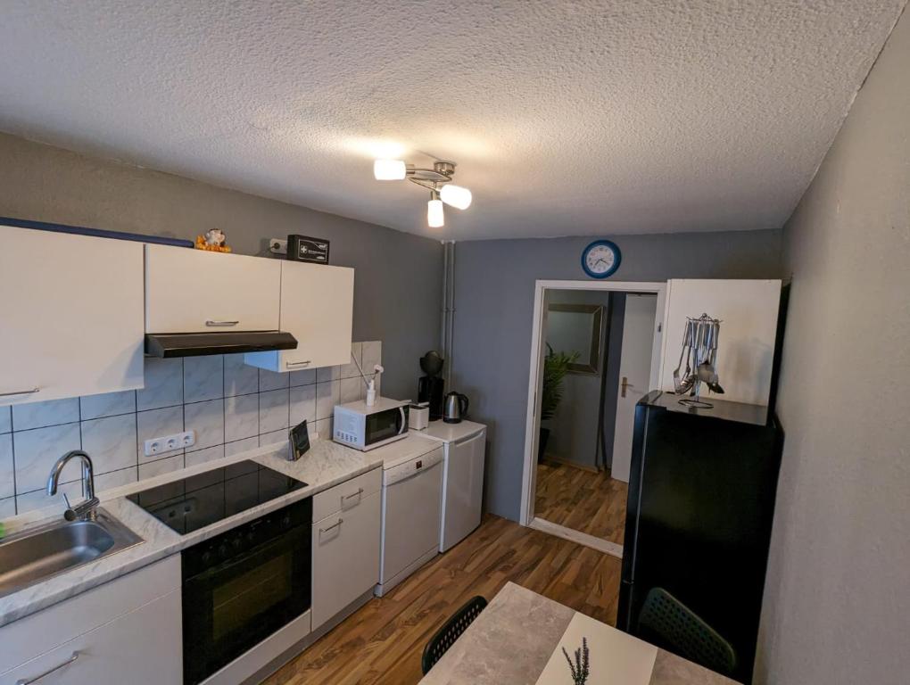 uma cozinha com armários brancos e um frigorífico preto em Flensburg Zentrum 50 em Flensburg