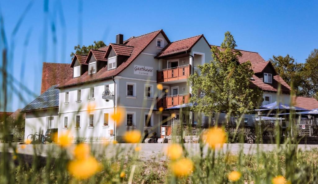 un grand bâtiment blanc avec un toit rouge dans l'établissement Gasthaus zur Linde, à Dombühl