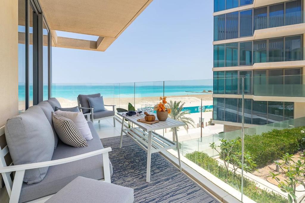 a balcony with a couch and a table and the ocean at Frank Porter - Al Saadiyat Island in Abu Dhabi