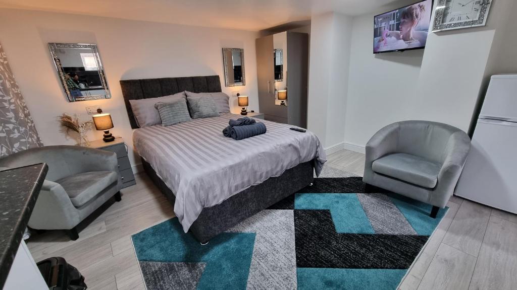 a bedroom with a large bed and two chairs at Comfy Studio apartment with Wi-Fi and Smart TV in Leeds