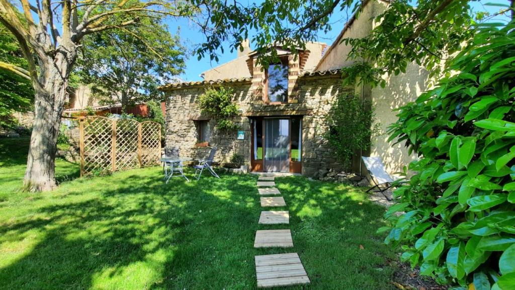 a stone house with a pathway in the yard at La petite maison dans la prairie in Cassaignes