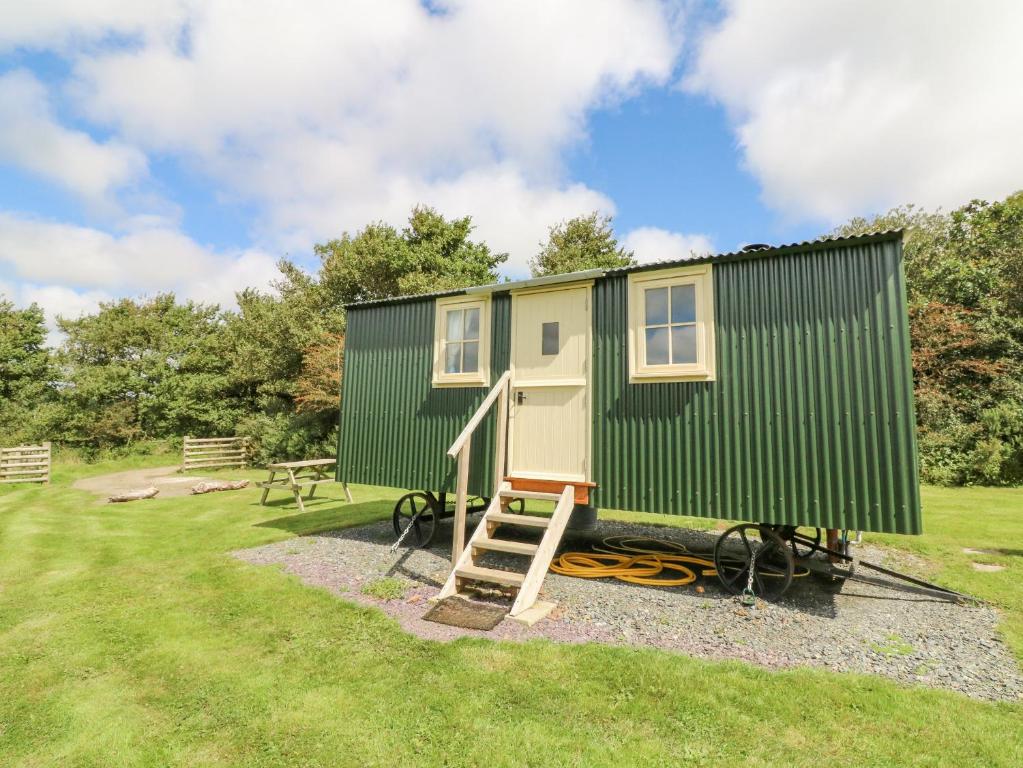 a green and yellow tiny house with a ladder at Westering Sun in Bude