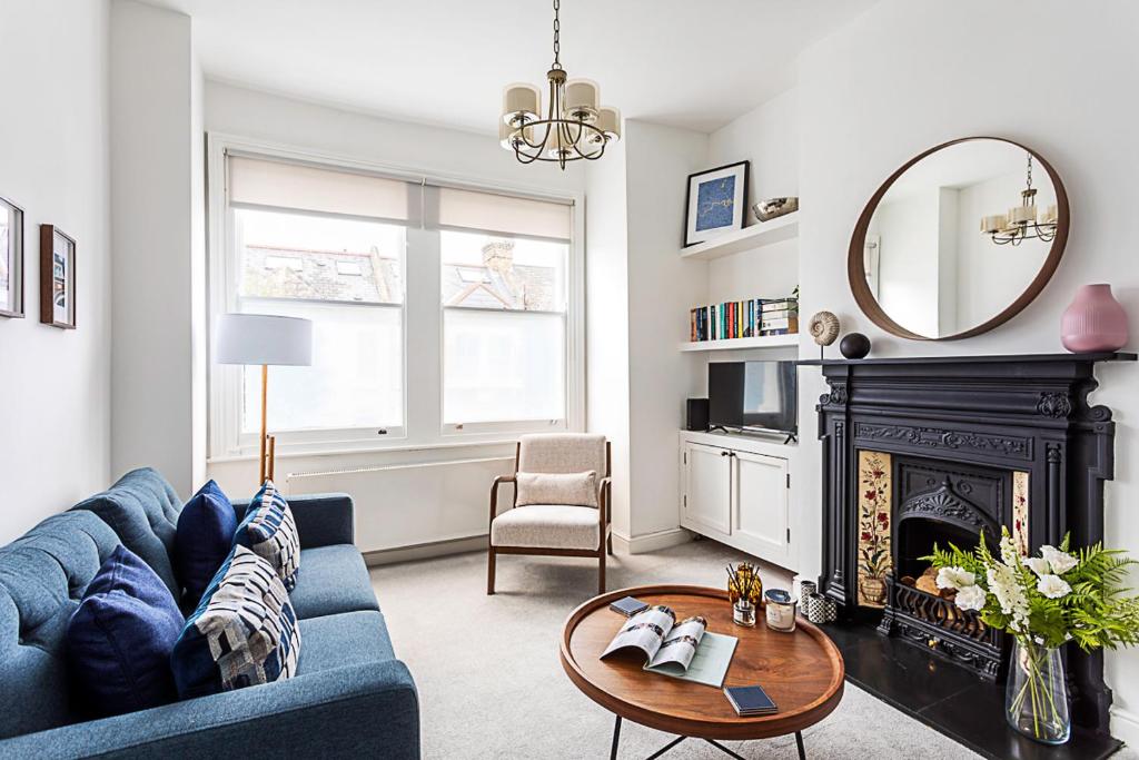 a living room with a blue couch and a fireplace at Gorgeous Clapham Flat in London