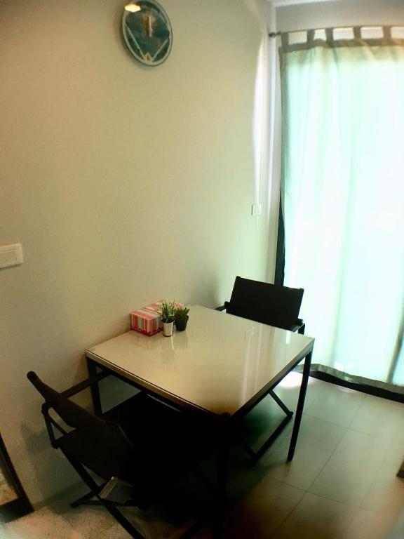 a dining room table with two chairs and a clock on the wall at the base 网红公寓 市中心核心区顶层无边泳池俯瞰整个芭堤雅海湾 in Pattaya