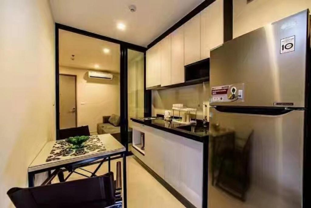 a small kitchen with a table and a refrigerator at the base 网红公寓 市中心核心区顶层无边泳池俯瞰整个芭堤雅海湾 in Pattaya