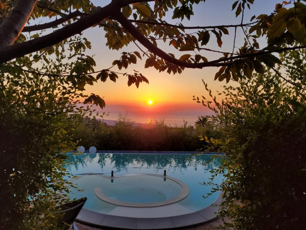 a sunrise over a swimming pool with the sun setting at Etna Sunshine Rent Rooms in Puntalazzo