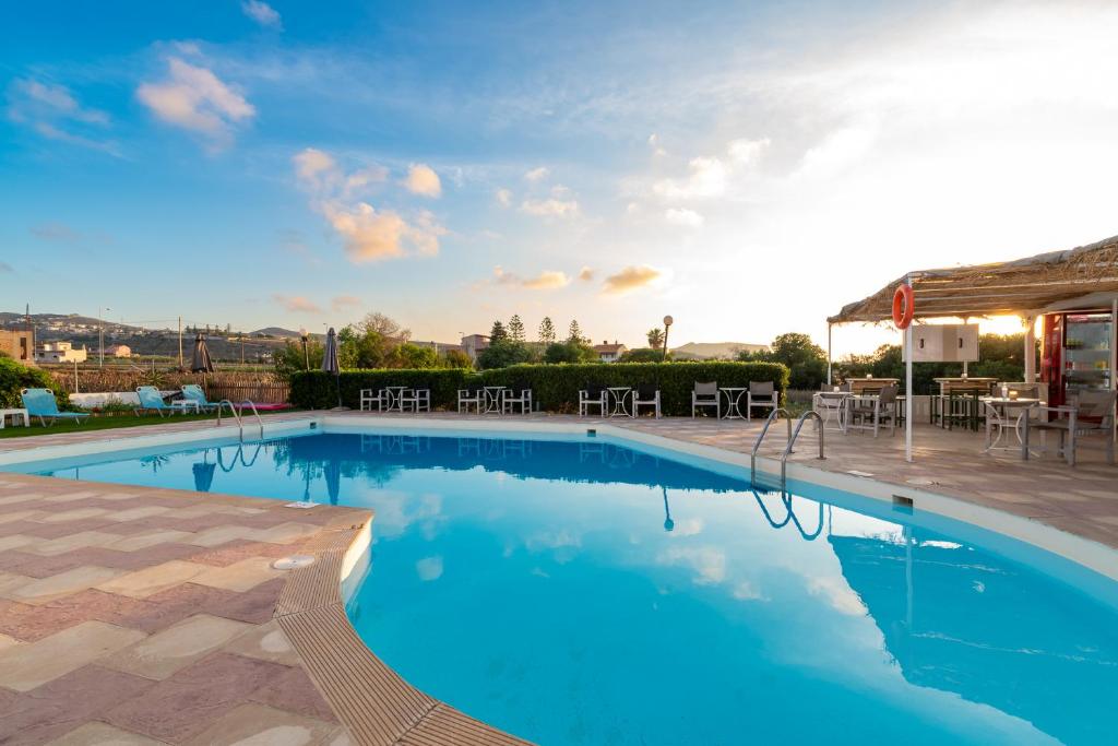 einen großen Pool mit einer Terrasse mit Tischen und Stühlen in der Unterkunft Anemos Inn by Estia in Kokkíni Khánion