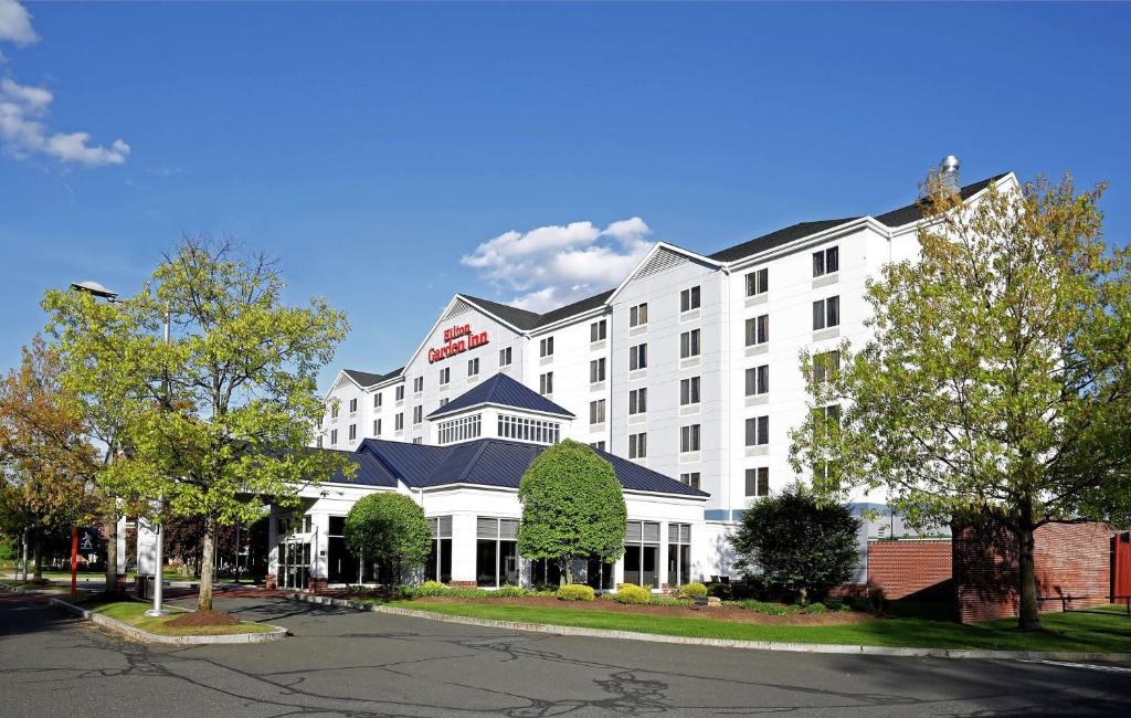 a white hotel building with a blue roof at Hilton Garden Inn Springfield, MA in Springfield