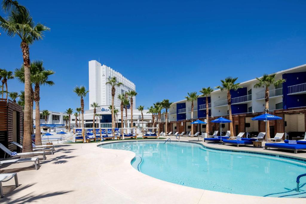 - une piscine avec des chaises et des palmiers dans l'établissement Tropicana Las Vegas a DoubleTree by Hilton Resort & Casino - Free Parking, à Las Vegas