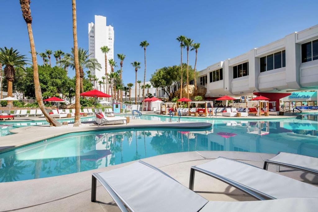 een zwembad in een hotel met stoelen en palmbomen bij Tropicana Las Vegas a DoubleTree by Hilton Resort & Casino - Free Parking in Las Vegas