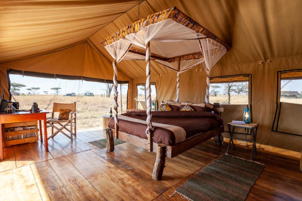 - une chambre avec un lit à baldaquin dans une tente dans l'établissement Mawe Tented Camp, à Serengeti