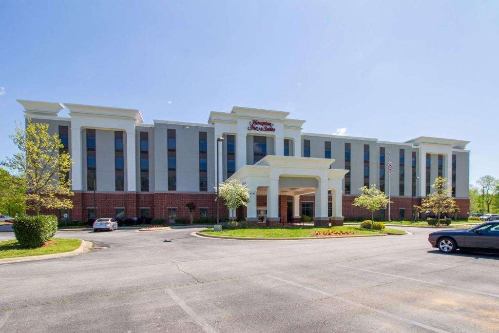 a large building with a car parked in a parking lot at Hampton Inn & Suites Huntsville Hampton Cove in Huntsville