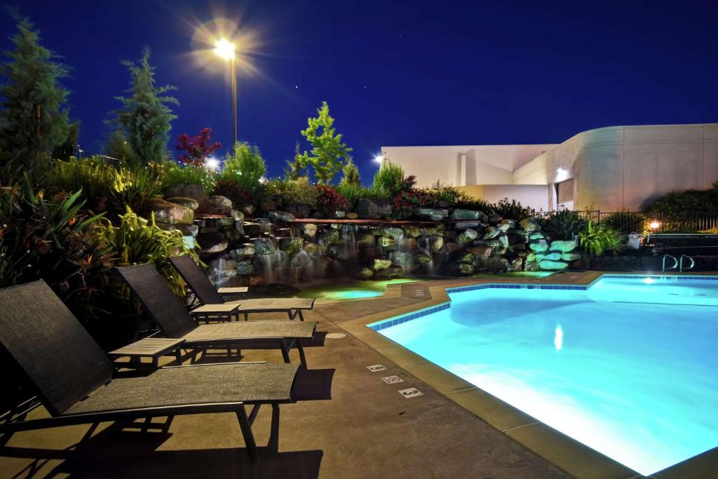 a swimming pool with benches and a house at night at DoubleTree by Hilton Pleasanton at The Club in Pleasanton