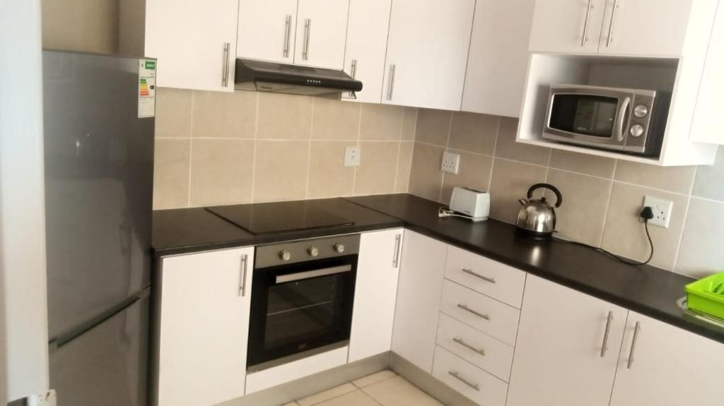 a kitchen with white cabinets and a black counter top at Despatch Self Catering Apartments in Despatch