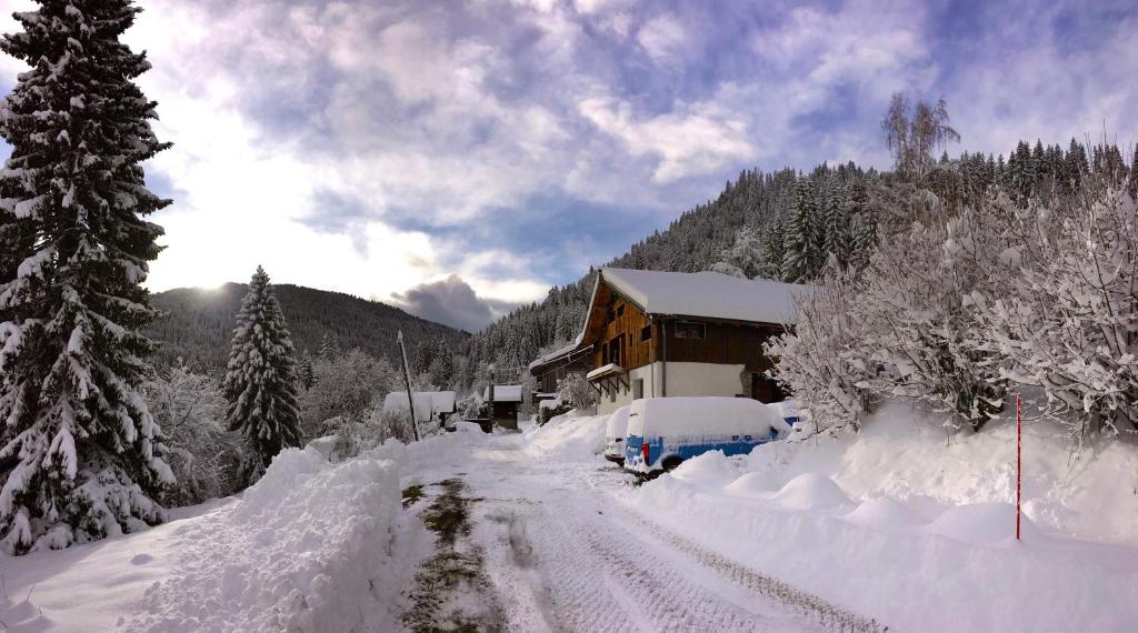 a house covered in snow next to a road at The Hideaway in Les Gets