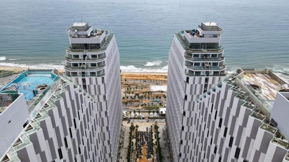 dois edifícios altos na praia com o oceano em Khách sạn 5* Apec Mandala Mũi Né - 1G 1m8 em Ấp Thiẹn Ái
