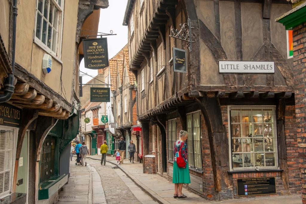 a woman in a green dress standing on a street at Assembly Cottage in Pocklington