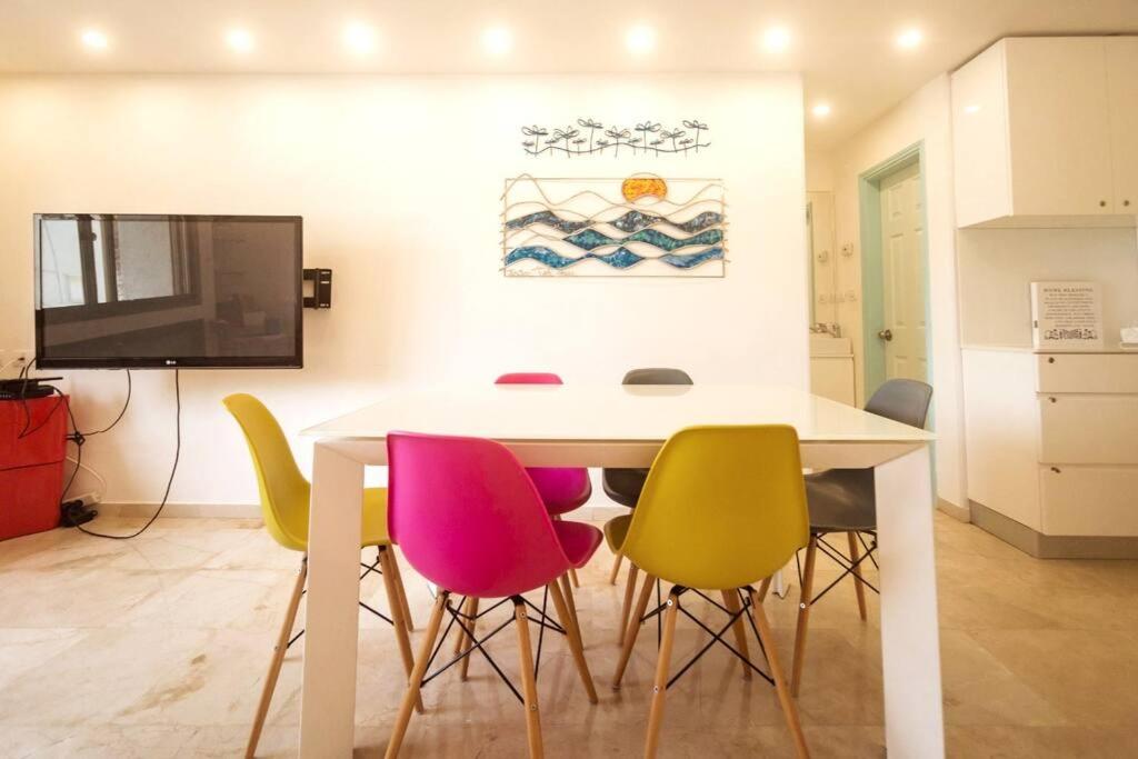 ein Esszimmer mit einem weißen Tisch und bunten Stühlen in der Unterkunft 2 bedrooms close to the Hilton in Tel Aviv
