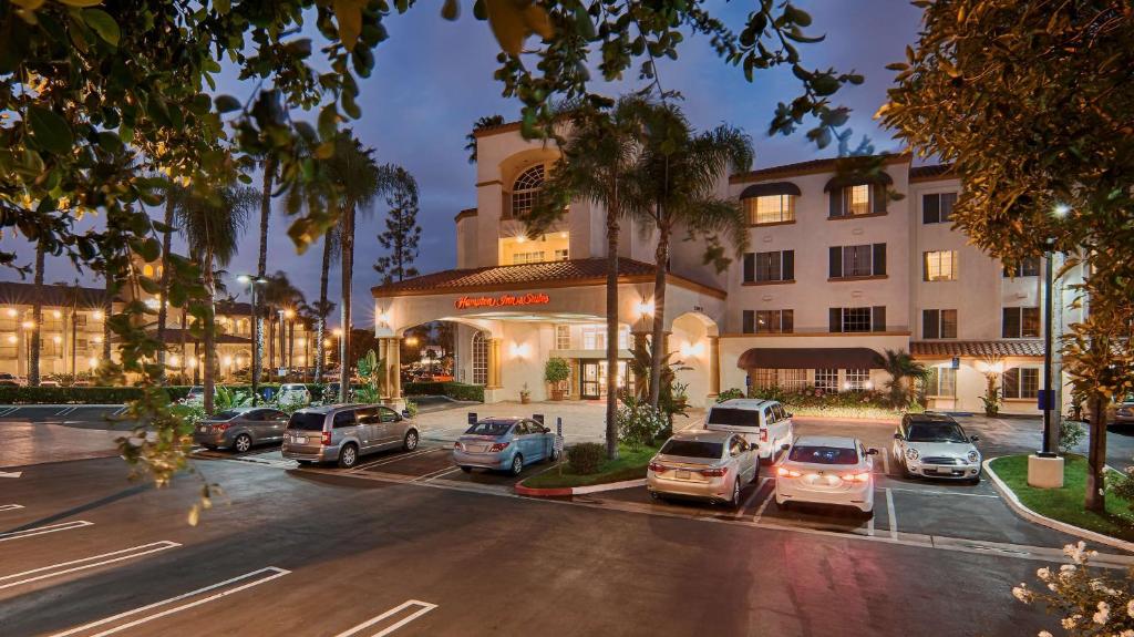 um parque de estacionamento com carros estacionados em frente a um edifício em Hampton Inn & Suites Santa Ana/Orange County Airport em Santa Ana