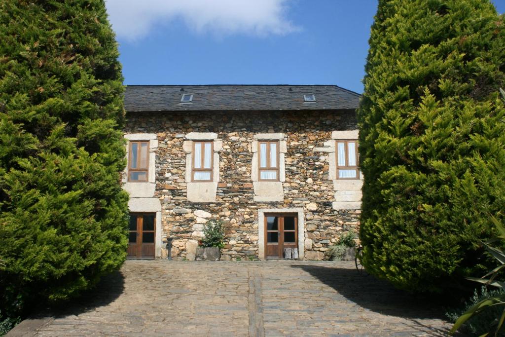 una antigua casa de piedra entre dos grandes árboles en Casa do Pinto en Arouca