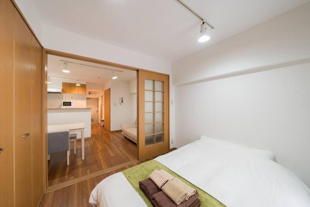 a bedroom with a white bed and a kitchen at Shibuya E Address 303 in Tokyo