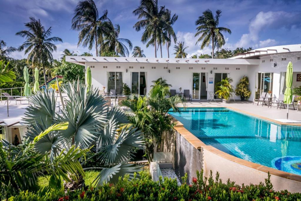 an exterior view of a house with a swimming pool and palm trees at The Inspiration Residence in Rawai Beach