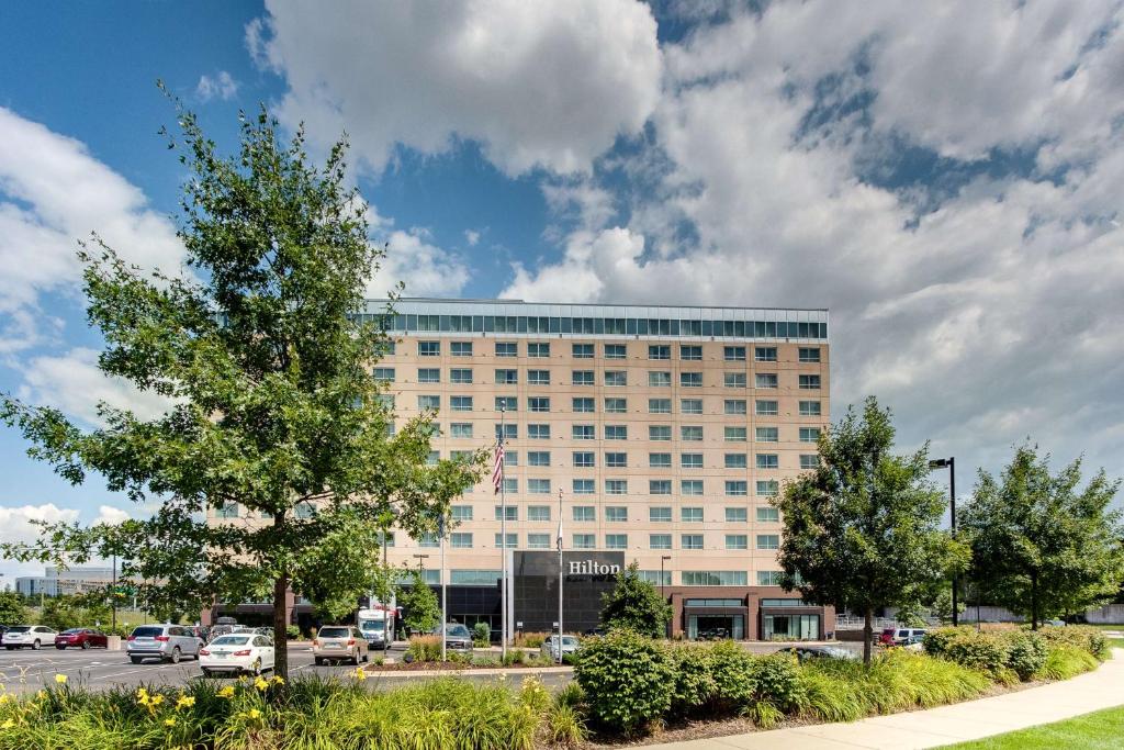 ein großes Gebäude mit Autos auf einem Parkplatz in der Unterkunft Hilton Minneapolis Bloomington in Bloomington