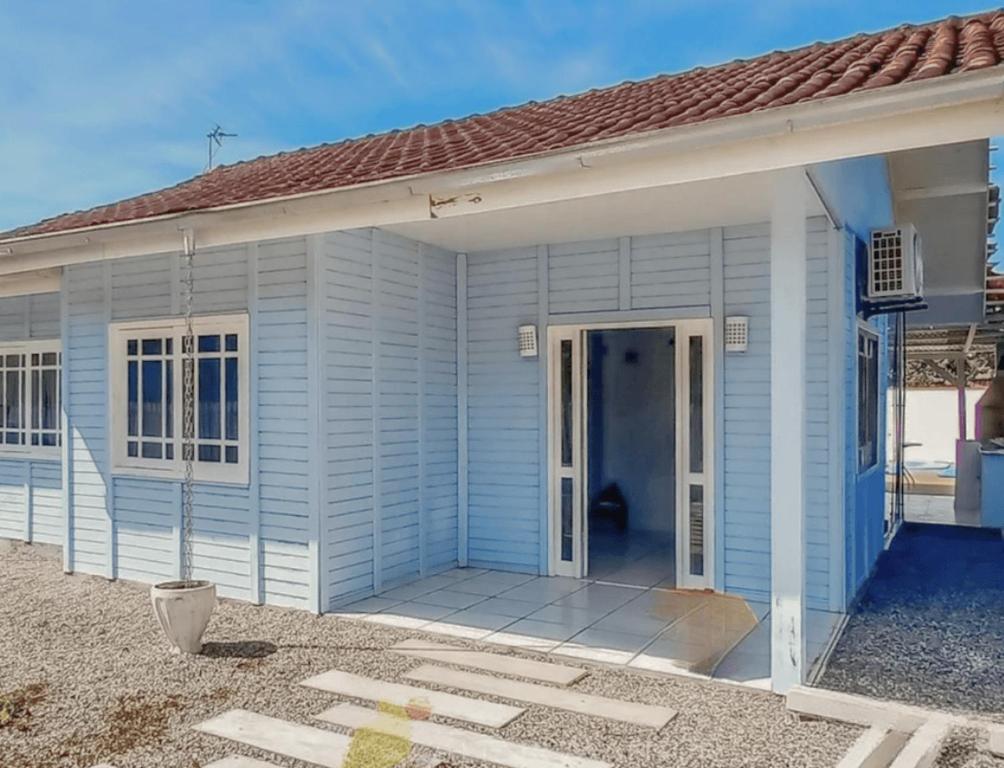 a small blue house with a large front porch at Casa Praia e Piscina in São Francisco do Sul