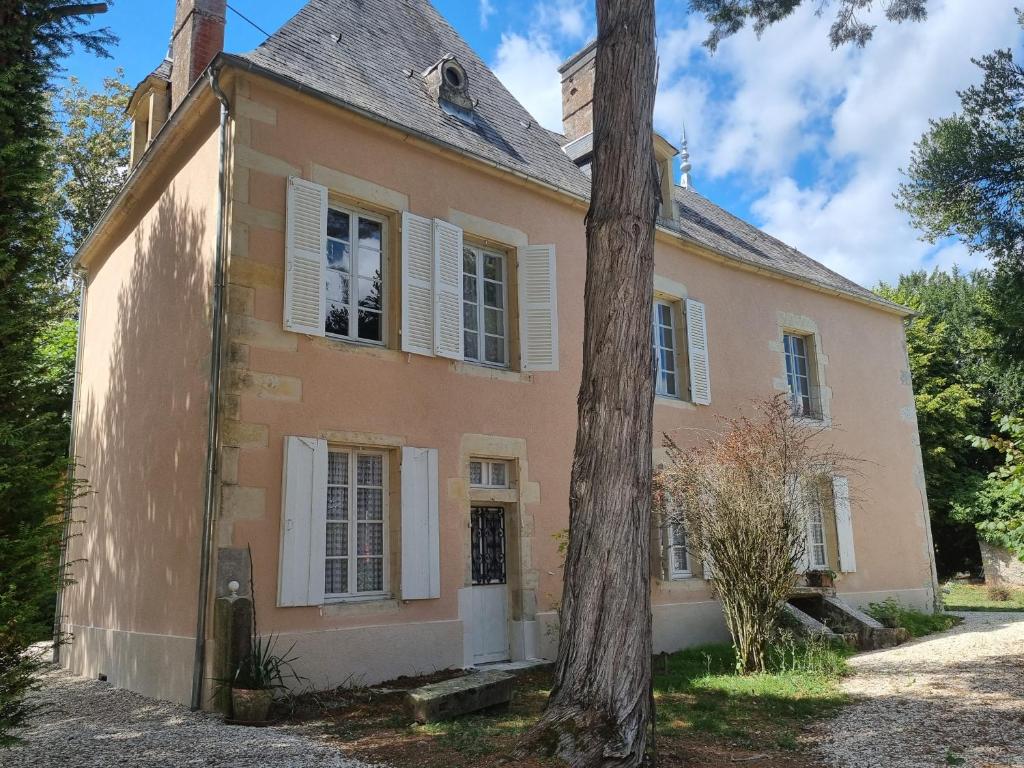 Una casa vieja con un árbol delante. en Gîte du château de Chevannes, en Amazy