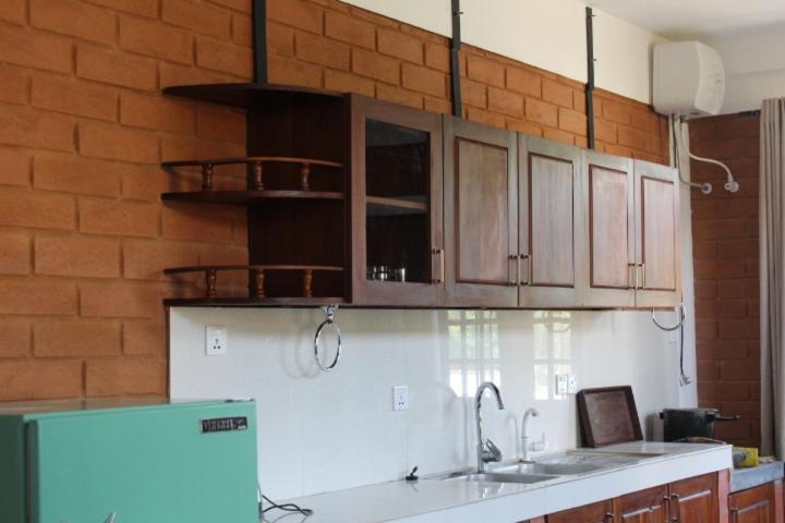 una cocina con armarios de madera y una pared de ladrillo en Windy Hanthana, en Kandy