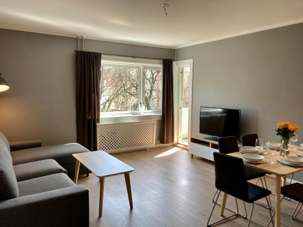 a living room with a couch and a table and a tv at Majorstua, charming and modern 2 bedroom apartment in Oslo
