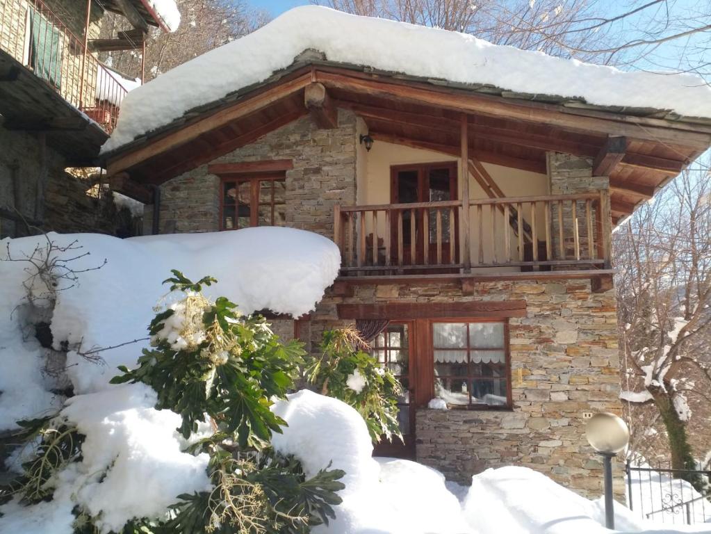 a log cabin with a balcony in the snow at L'ontano sulle Alpi in Villar Pellice